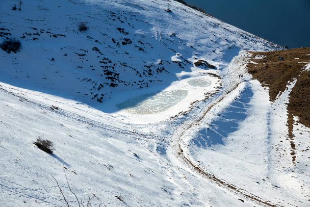 verschneite Berglandschaft mit kleinem zugefrorenen See - Foto, Bild