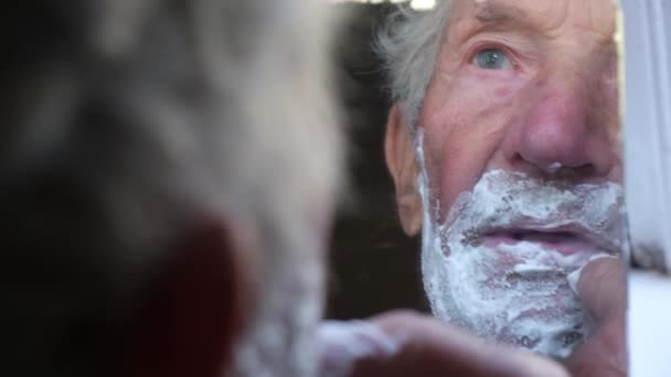 巻き毛の老人は髭を生やしていて、鏡を手に持っている。灰色の祖父 - 映像、動画