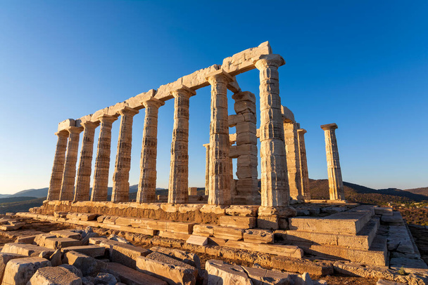 Ruiny starożytnej świątyni Posejdona na greckim przylądku Sounio. Posejdon jest greckim bogiem morza. Strzał ruin świątyni o zachodzie słońca. Atrakcja turystyczna Attica, Sounion, Grecja. - Zdjęcie, obraz
