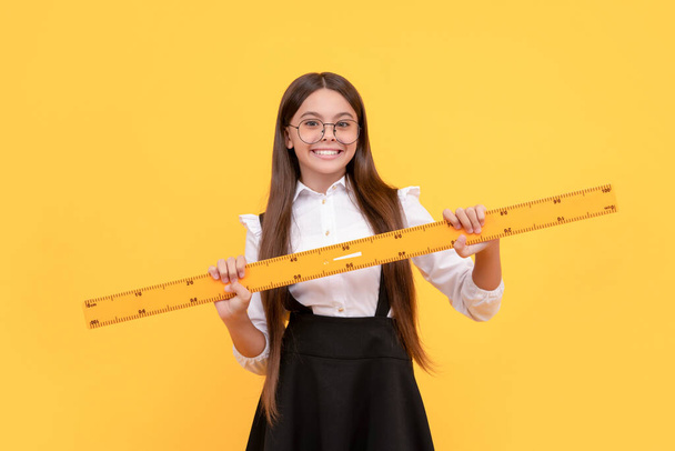 niño feliz en uniforme escolar y gafas sostienen regla matemática para medir, geometría - Foto, Imagen