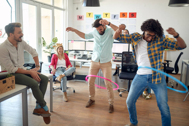 Un gruppo di dipendenti si sta divertendo giocando con hula-hoop in un'atmosfera rilassata in ufficio. Dipendenti, lavoro, ufficio - Foto, immagini
