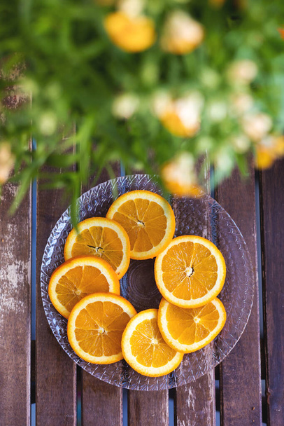 Tányér narancssárga fából készült asztallal, citrusszeletek, friss gyümölcsök - Fotó, kép