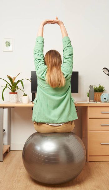Woman stretching while working from home remotely - Photo, Image
