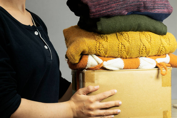closeup γυναίκα βάζοντας πουκάμισο σε χαρτοκιβώτιο με μεταχειρισμένα ρούχα για τη δωρεά, τη συλλογή και την υποστήριξη των θυμάτων πολέμου, βοηθώντας τους ανθρώπους, φιλανθρωπία - Φωτογραφία, εικόνα