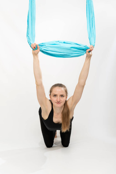 Młoda kobieta ćwiczy dla elastyczności i rozciągania. Ćwiczenia z jedwabnym hamakiem. Portret na białym tle - Zdjęcie, obraz