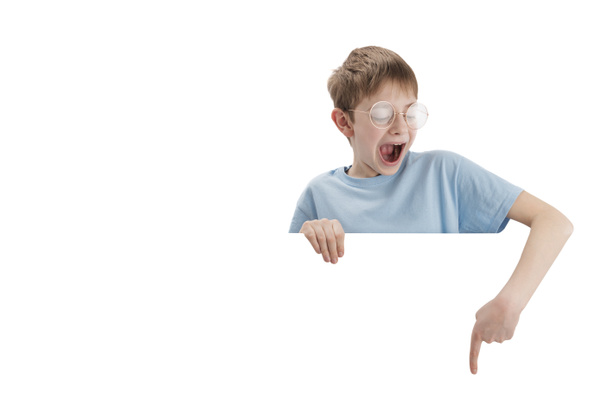 Surprised teenage boy points his finger down at empty space. Portrait of impressed schoolboy isolated on white background. Copy space - Photo, Image