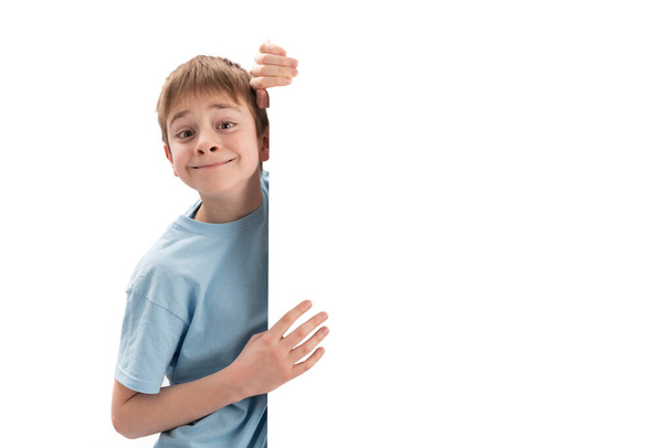 Gülen çocuk boş beyaz tahtayla poz veriyor. Elinde boş afiş olan bir çocuğun portresi. Boşluğu kopyala - Fotoğraf, Görsel