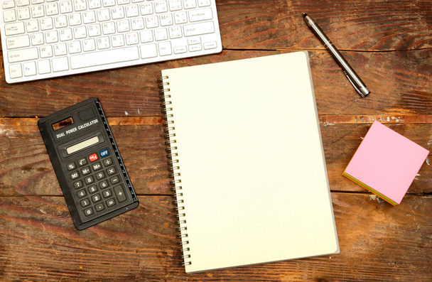 escritorio: concepto de impuestos, cuaderno vacío, calculadora y teclado y pluma y nota adhesiva en la mesa de madera - Foto, imagen