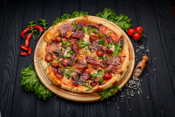 Delicious pizza with prosciutto and arugula. Italian snacks. Top view. - 写真・画像