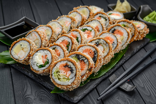 Set of hot sushi rolls in tempura. Assortment of delicious tempura and baked sushi maki with salmon, eel, cucumber, avocado, scrambled eggs, shrimp. Japanese oriental cuisine - Photo, Image