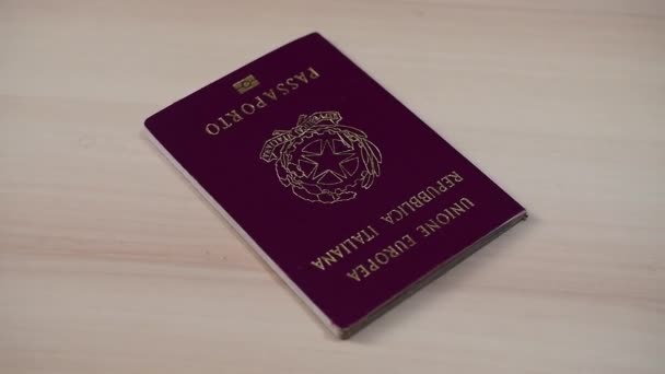 Pasaporte italiano girar en cámara lenta sobre una mesa de madera - Imágenes, Vídeo