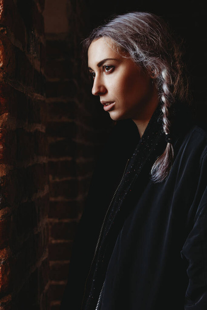 Side view of beautiful young hipster woman with braids in mixed contrast light - Foto, imagen