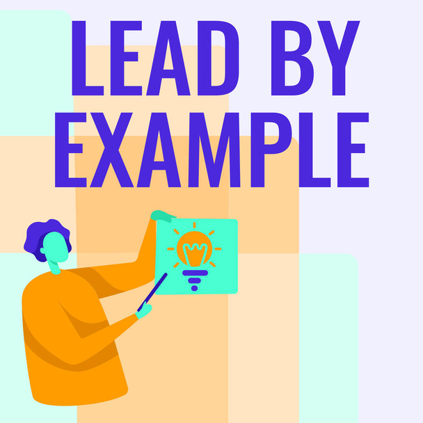 Text sign showing Lead By Example. Internet Concept Be a mentor leader follow the rules give examples Coach Man Standing Holding Paper With Glowing Light Bulb While Pointing Stick. - Photo, Image