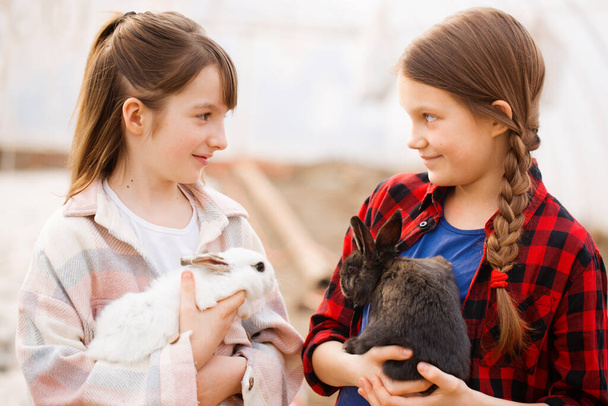 Deux filles tenant des lapins dans leurs mains. Concept de Pâques - Photo, image