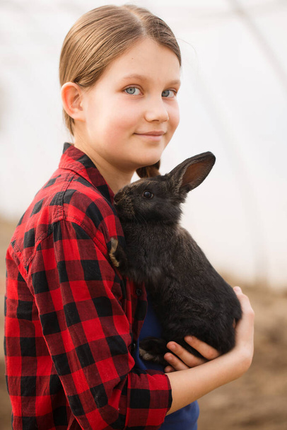 Retrato de uma rapariga com um coelho negro nas mãos. Conceito de Páscoa - Foto, Imagem