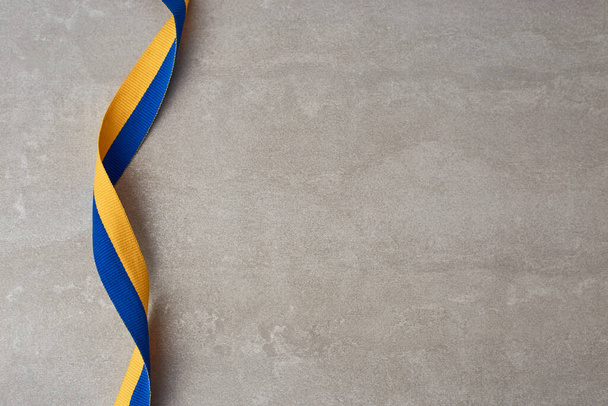 Ukrainian national flag colors on grey background. fabric ribbon of Yellow and blue colors. Copy space - Photo, image