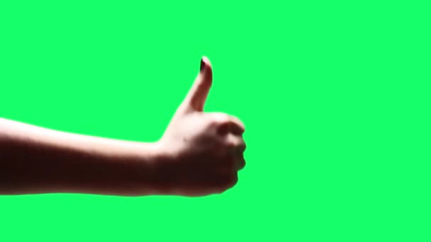 クロマの背景を上下に親指を示す女性の手。緑の画面を必要な映像や画像に置き換えることができます。After Effectsやその他のビデオ編集ソフトウェアでキーエフェクトを使用することができます(チュートリアルを確認してください) 。).   - 映像、動画