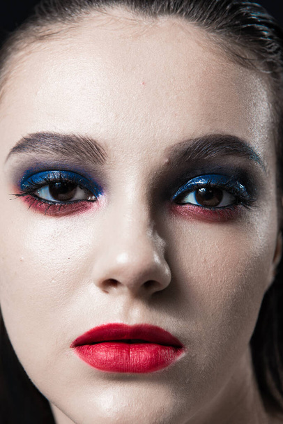 Retrato de belleza creativa con labios rojos y ojos azules sobre un fondo negro  - Foto, Imagen