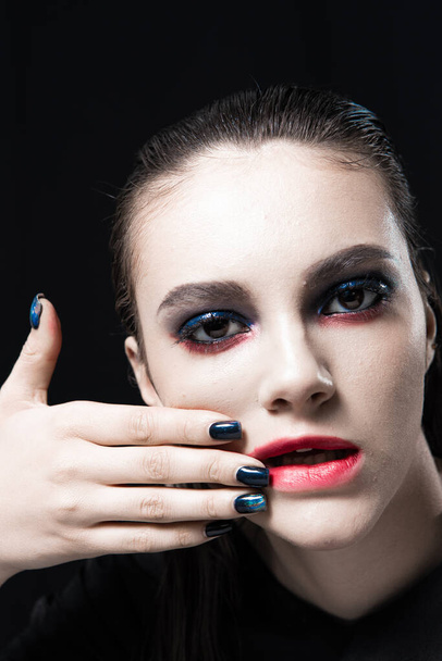 Πορτρέτο δημιουργικής ομορφιάς με κόκκινα χείλη και μπλε μάτια σε μαύρο φόντο  - Φωτογραφία, εικόνα