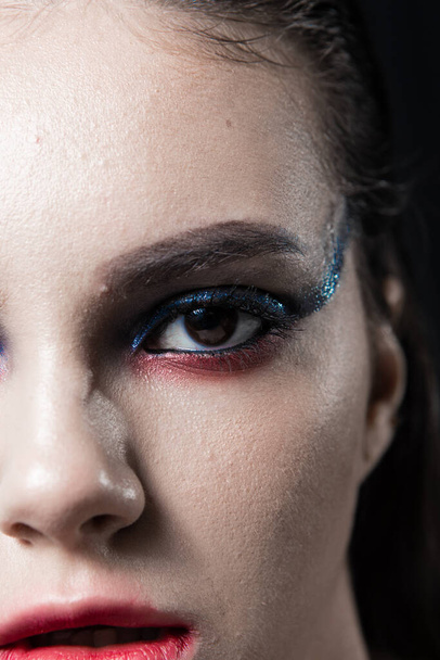 Creatieve schoonheid Portret met rode lippen en blauwe ogen op een zwarte achtergrond  - Foto, afbeelding