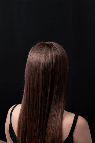 Mooi glanzend en schoon haar, nette kapsel op een zwarte achtergrond  - Foto, afbeelding