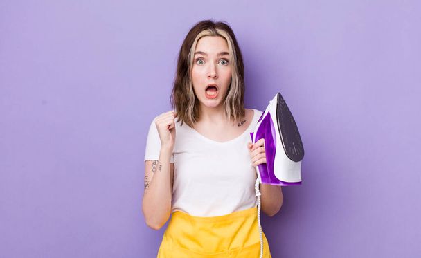 pretty caucasian woman feeling shocked,laughing and celebrating success. hand iron concept - Photo, image