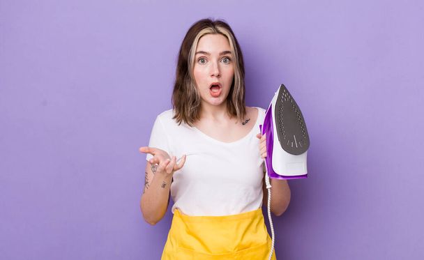 pretty caucasian woman feeling extremely shocked and surprised. hand iron concept - 写真・画像