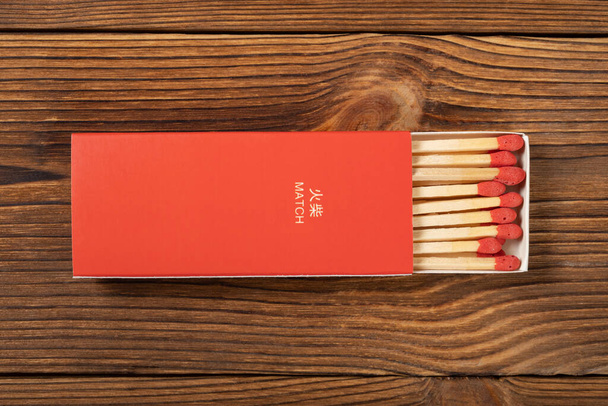 木製のテーブルの上に赤いマッチ棒付きの赤い色のマッチ箱を表示 - 写真・画像