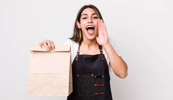 pretty hispanic woman feeling happy,giving a big shout out with hands next to mouth. delivery and take away concept - Photo, image