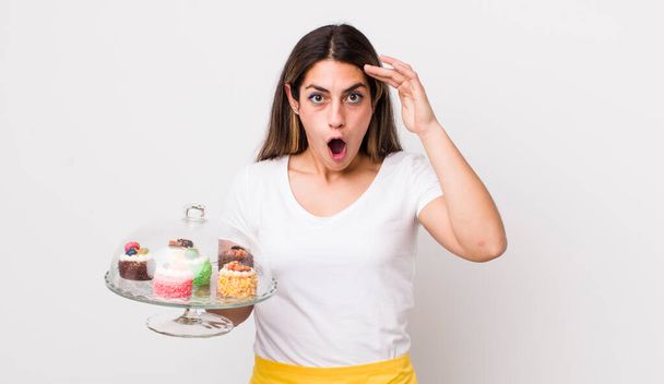 pretty hispanic woman looking happy, astonished and surprised. home made cakes concept - Fotó, kép