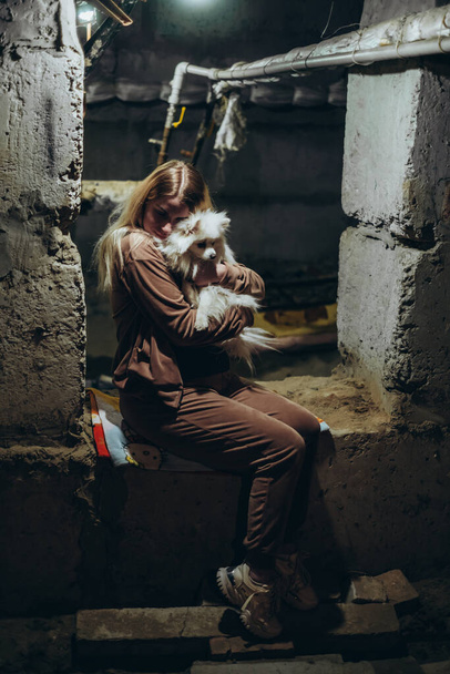 Krieg in der Ukraine. Eine Ukrainerin versteckt sich mit einem Hund in einem Luftschutzbunker und widersetzt sich einer russischen Invasion. - Foto, Bild