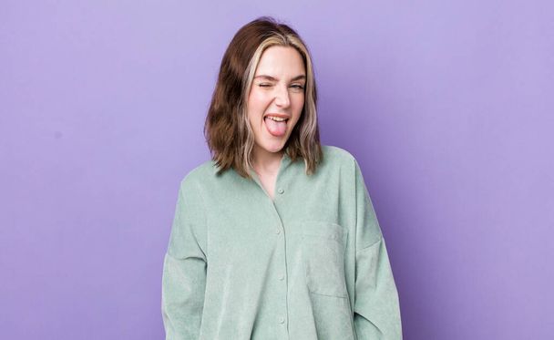 pretty caucasian woman with cheerful, carefree, rebellious attitude, joking and sticking tongue out, having fun - 写真・画像
