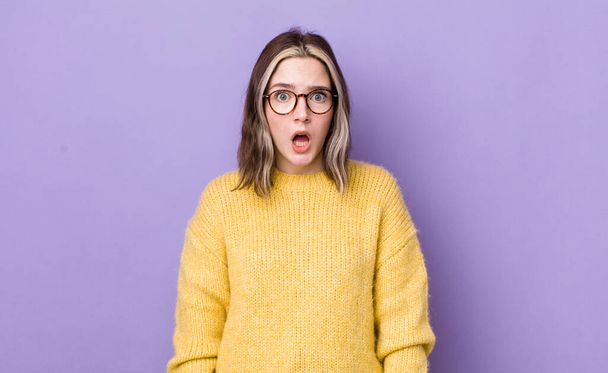 pretty caucasian woman feeling terrified and shocked, with mouth wide open in surprise - Фото, изображение