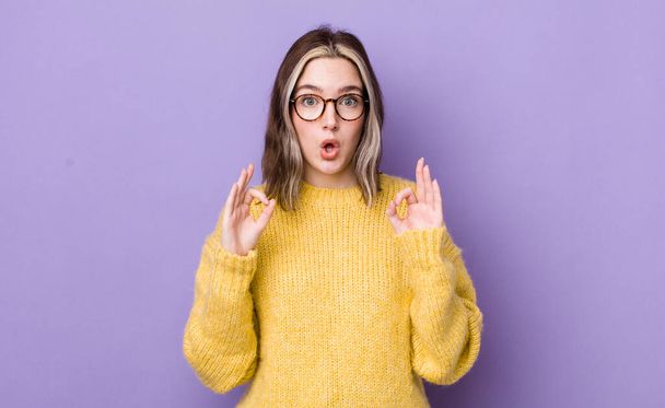 pretty caucasian woman feeling shocked, amazed and surprised, showing approval making okay sign with both hands - Foto, Bild