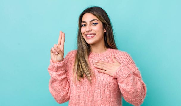 pretty hispanic woman looking happy, confident and trustworthy, smiling and showing victory sign, with a positive attitude - Foto, Imagen