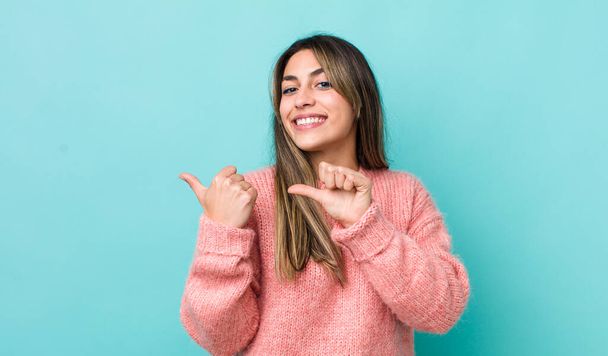 pretty hispanic woman smiling cheerfully and casually pointing to copy space on the side, feeling happy and satisfied - Photo, image