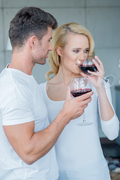 Νεαρό ζευγάρι απολαμβάνει ένα ποτήρι κόκκινο κρασί - Φωτογραφία, εικόνα