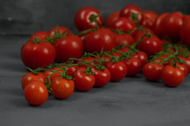 A group of different tomatoes on the vine on grey stone background. Concept for healthy nutrition. Symbolic image. - Φωτογραφία, εικόνα