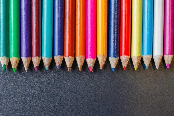 Le matite colorate sono impilate su una scrivania nera nell'ufficio del designer in preparazione per una scelta rapida e facile dei colori di design. Un sacco di sfondi colorati pastello per il design e progettisti. - Foto, immagini