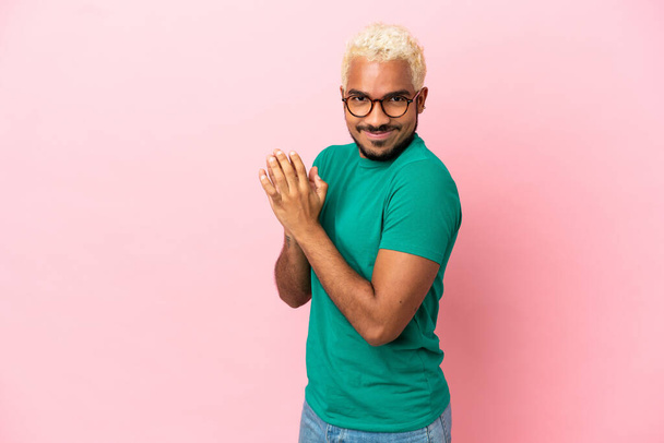 Young Colombian handsome man isolated on pink background scheming something - Photo, Image