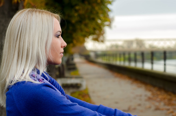 Kaunis nuori nainen istuu ulkona pilvinen syyspäivä
 - Valokuva, kuva