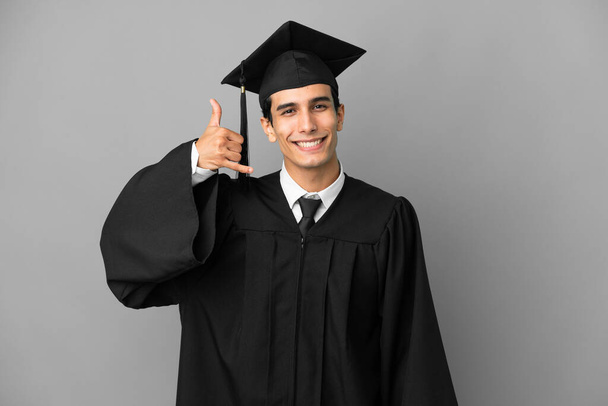 若いアルゼンチンの大学の卒業生は灰色の背景に電話ジェスチャーを作る隔離された。サインを呼んでくれ - 写真・画像