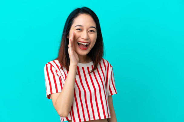 Young Vietnamese woman isolated on blue background shouting with mouth wide open - Photo, Image