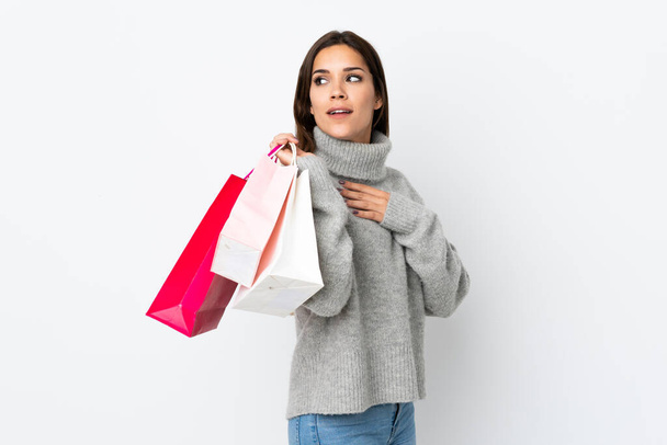 Joven mujer caucásica aislada sobre fondo blanco sosteniendo bolsas de compras y sonriendo
 - Foto, imagen