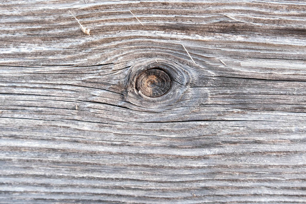 Поверхность старой, коричневой деревянной доски с местом от ветки, похожим на глаз. - Фото, изображение