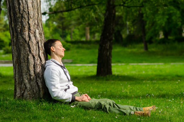 Jovem feliz relaxando no parque no dia ensolarado da primavera
 - Foto, Imagem