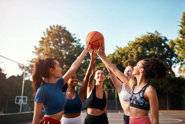 Ας το κάνουμε, κορίτσια. Τραβηγμένο πλάνο από μια διαφορετική ομάδα αθλητριών που κρατούν ένα μπάσκετ μαζί πριν παίξουν ένα παιχνίδι κατά τη διάρκεια της ημέρας. - Φωτογραφία, εικόνα