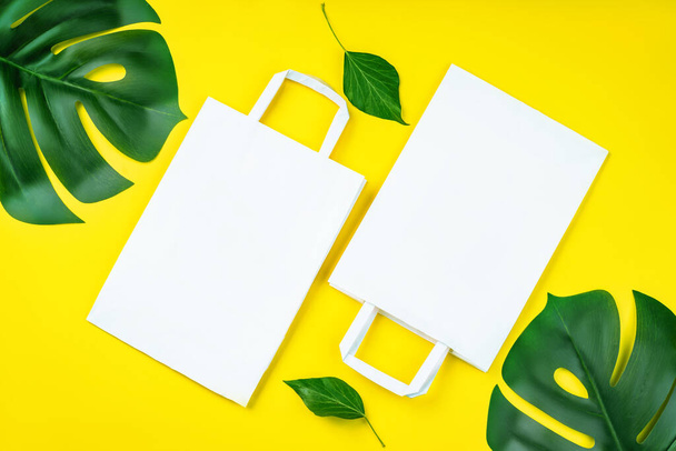 Eco-friendly paper bags on yellow background.Recycled paper shopping bag with green leaves on yellow background. Zero waste, plastic-free concept. Environmental protection, sustainable living - Foto, Imagem