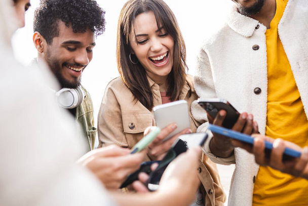 Junge Gruppe von Menschen lacht mit Handy im Freien - Foto, Bild