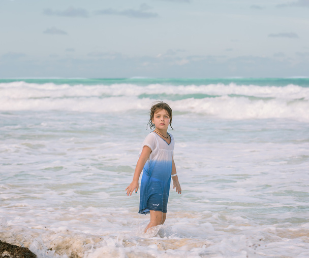 Niña solitaria caminando en el océano Atlántico cerca de la playa en el soleado y cálido día de verano
 - Foto, Imagen